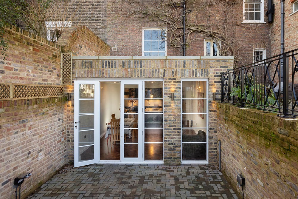 Rear extension with traditional wooden doors opening onto a patio at St Germans Place, Blackheath, London, designed and built by MVV