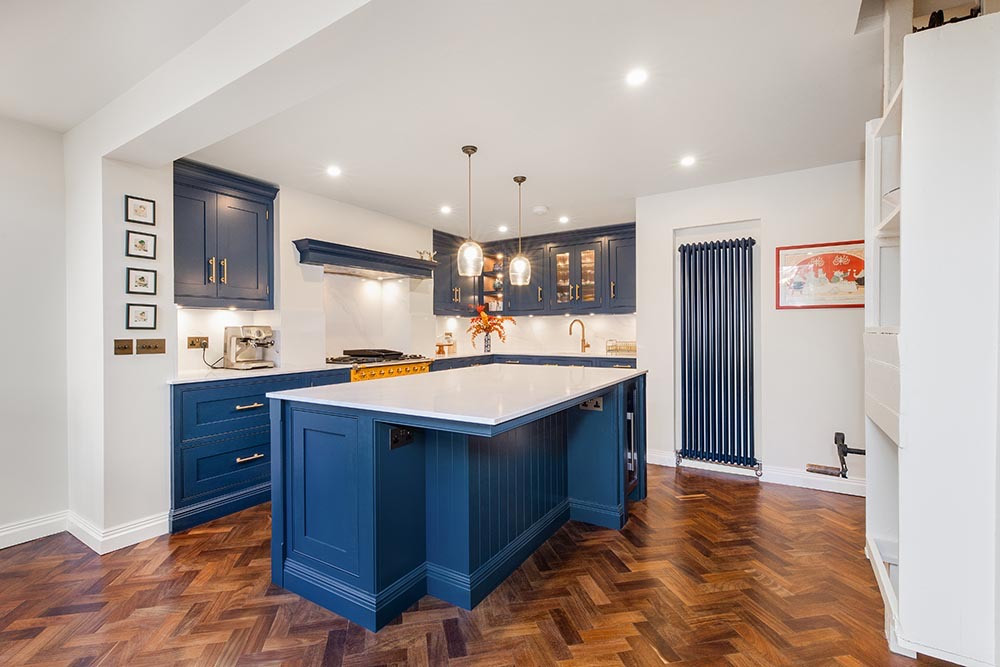 An open kitchen with a blue island and a dining table beyond, in a rear extension in Blackheath.