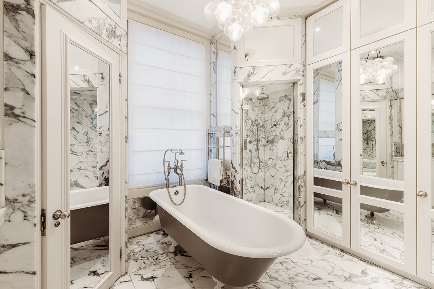 Marble bathroom with a freestanding bath and mirrored joinery at Margaretta Terrace, Chelsea, London, designed and built by MVV