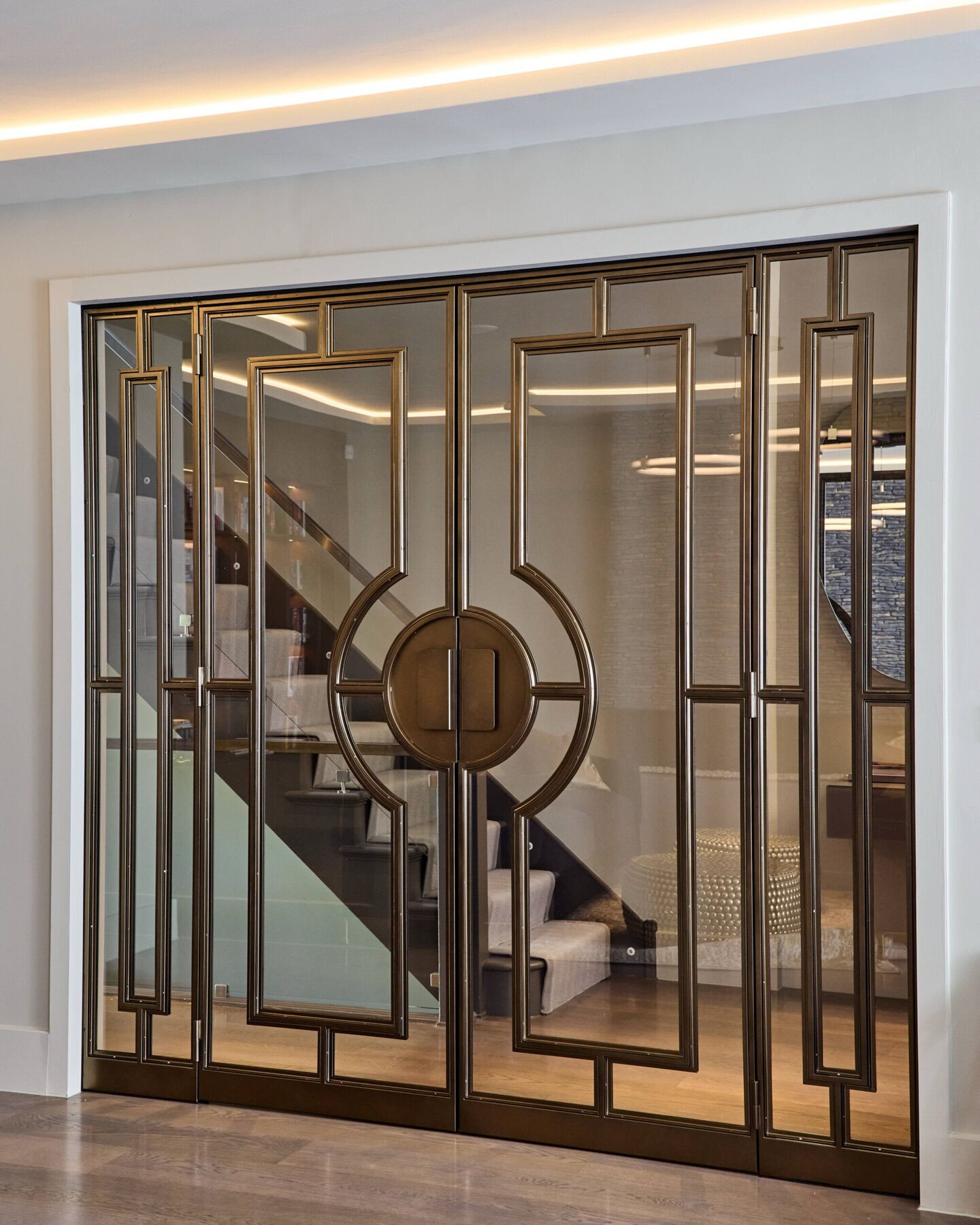 Glazed doors in a bronze-coloured geometric frame at Ellerby Street, Fulham, with the staircase behind them.